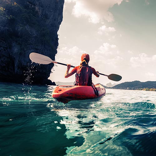 Kayaker passing a looming cliff